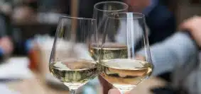 three people having a toast using three clear crystal wine glasses