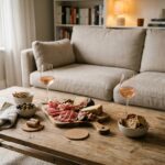 Apéro maison convivial avec plateau de charcuterie, olives et verres de rosé sur une table basse en bois rustique dans un salon cosy