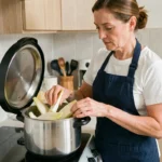 Femme préparant des endives dans une cocotte minute sur un plan de cuisson domestique