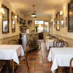 Intérieur authentique d'un bistrot parisien traditionnel avec comptoir en zinc, tables en bois et ardoise de menu manuscrit