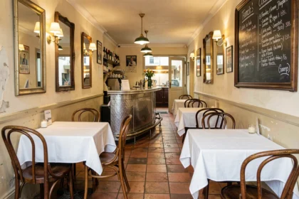 Intérieur authentique d'un bistrot parisien traditionnel avec comptoir en zinc, tables en bois et ardoise de menu manuscrit