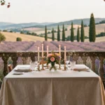 Table dressée pour deux sur une terrasse en pierre avec vue sur les collines de Provence et des champs de lavande en arrière-plan, évoquant un dîner romantique dans le sud de la France
